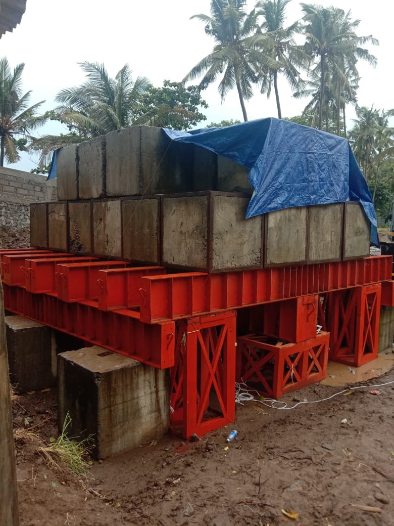 Susunan blok beton metode Kentledge di atas platform baja oranye pada kondisi lapangan proyek.