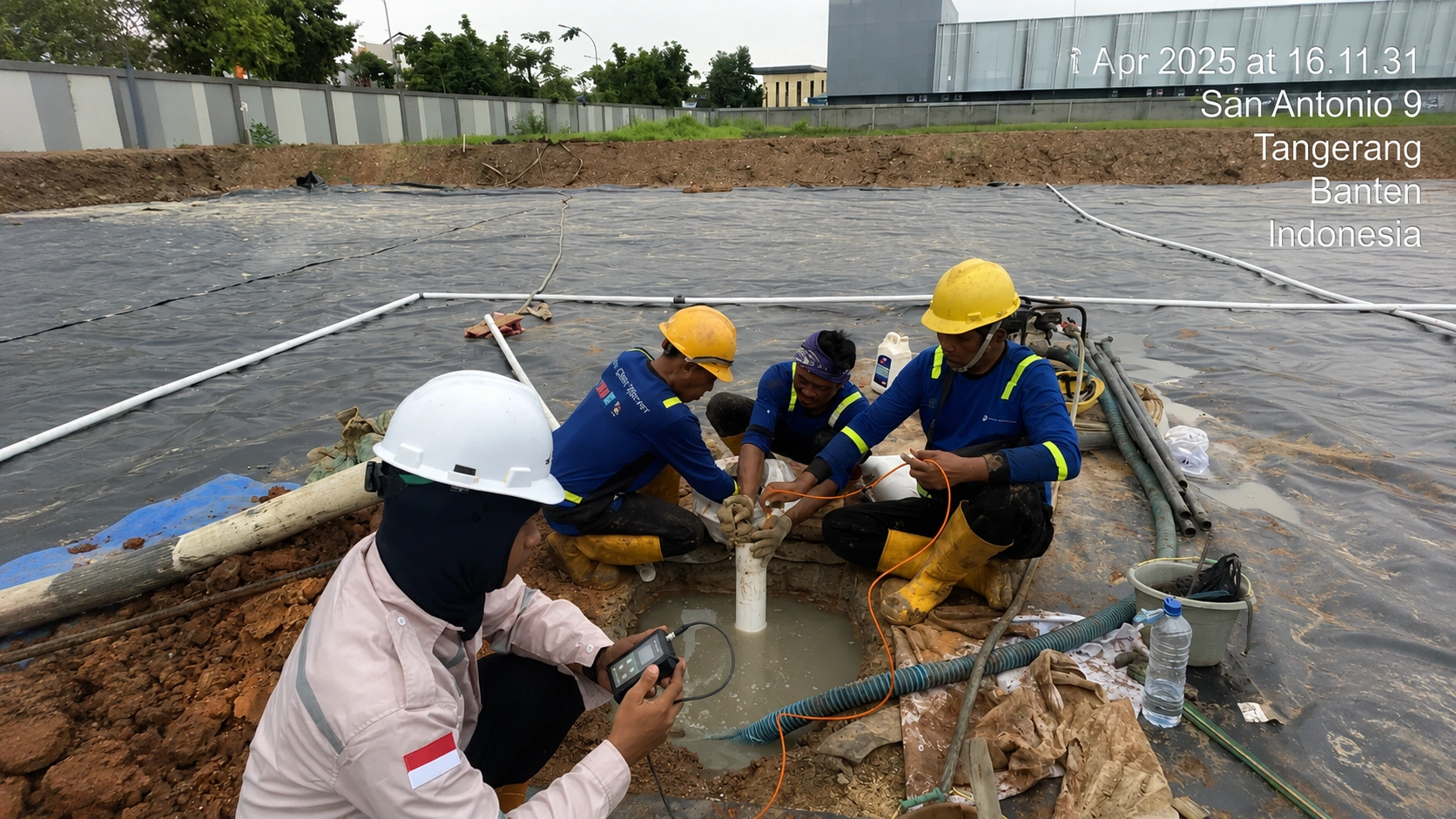 Teknisi geoteknik melakukan pemasangan pipa standpipe di lubang bor lapangan
